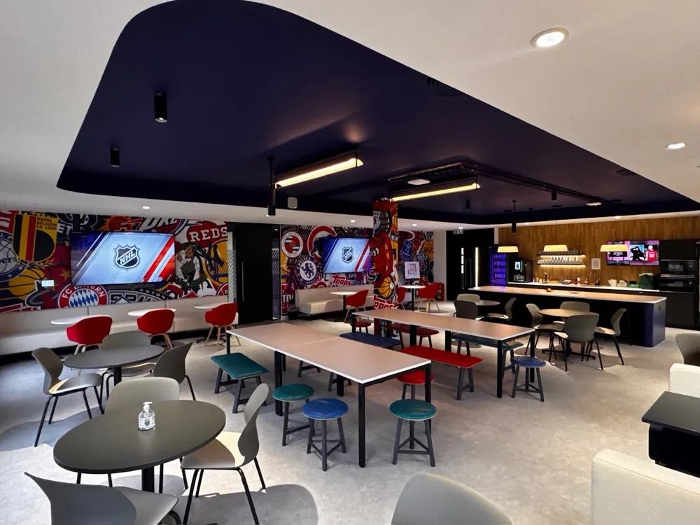 Staff dining and social space with wall-mounted screens above the seating areas